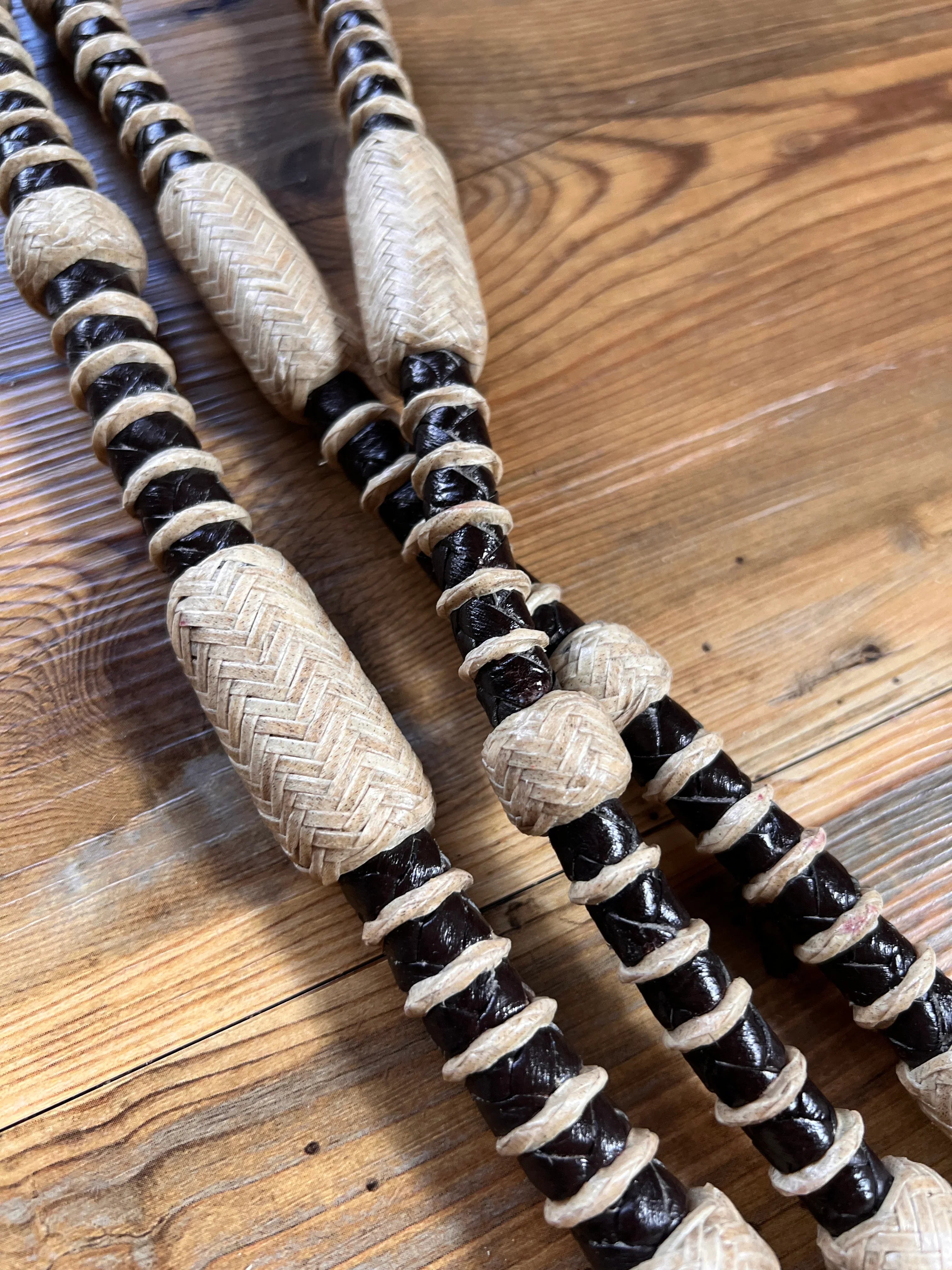 Black and beige woven rope-handled 10-plait romal reins, 55 inches