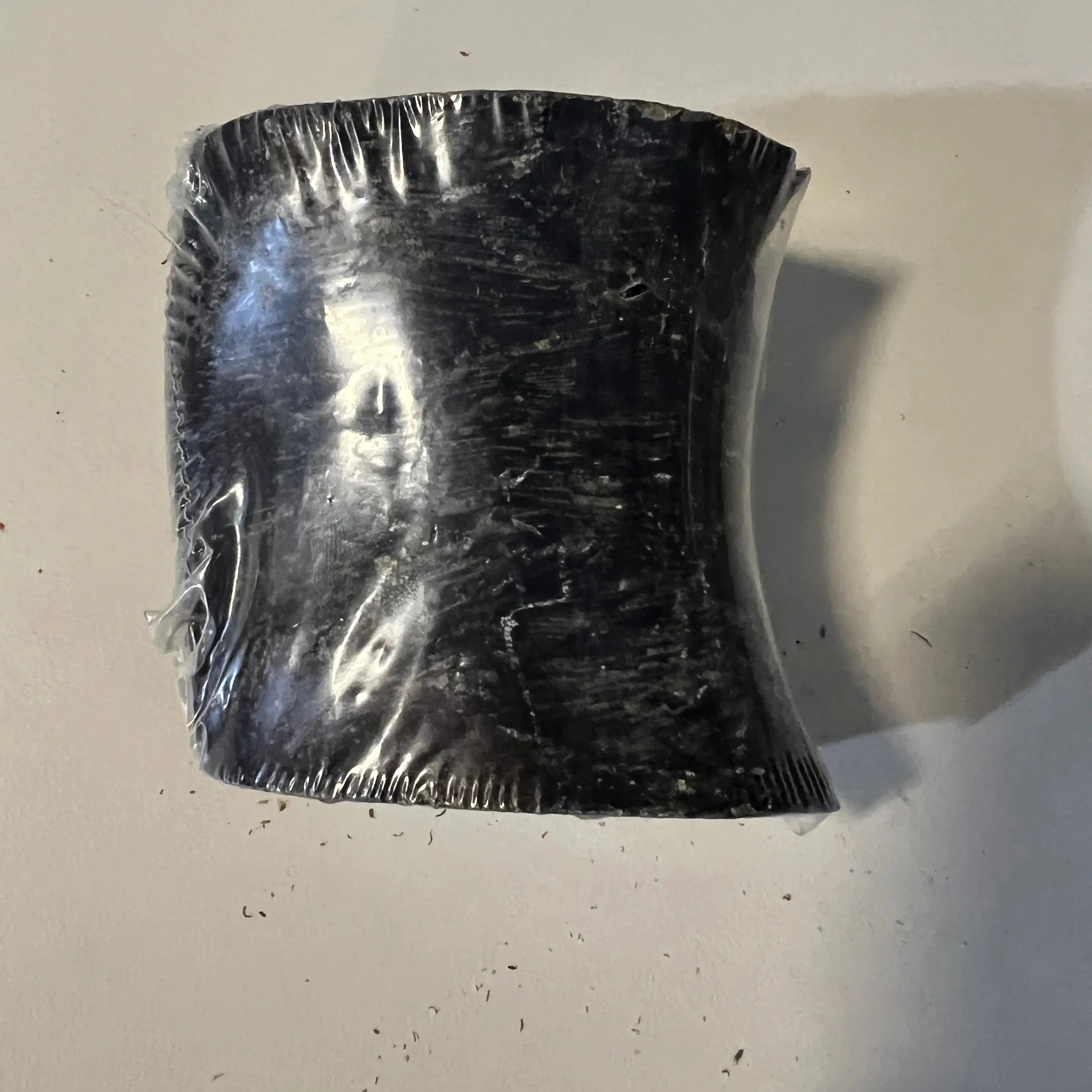 Peanut Butter Stuffed Horn: black curved plastic-wrapped textured dog treat