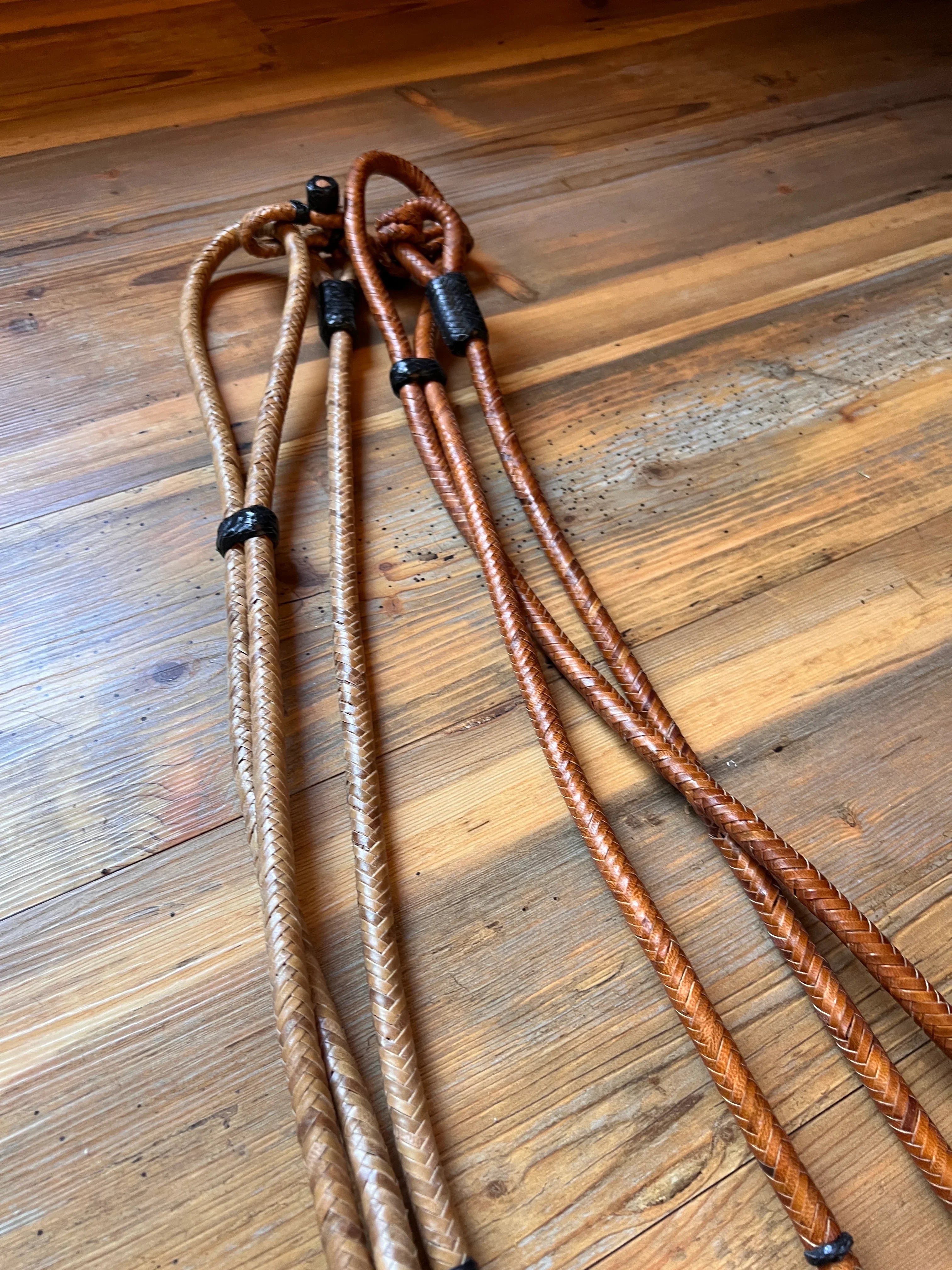Brown braided leather lanyards with black plastic clasps on Romal Reins with Black Rawhide