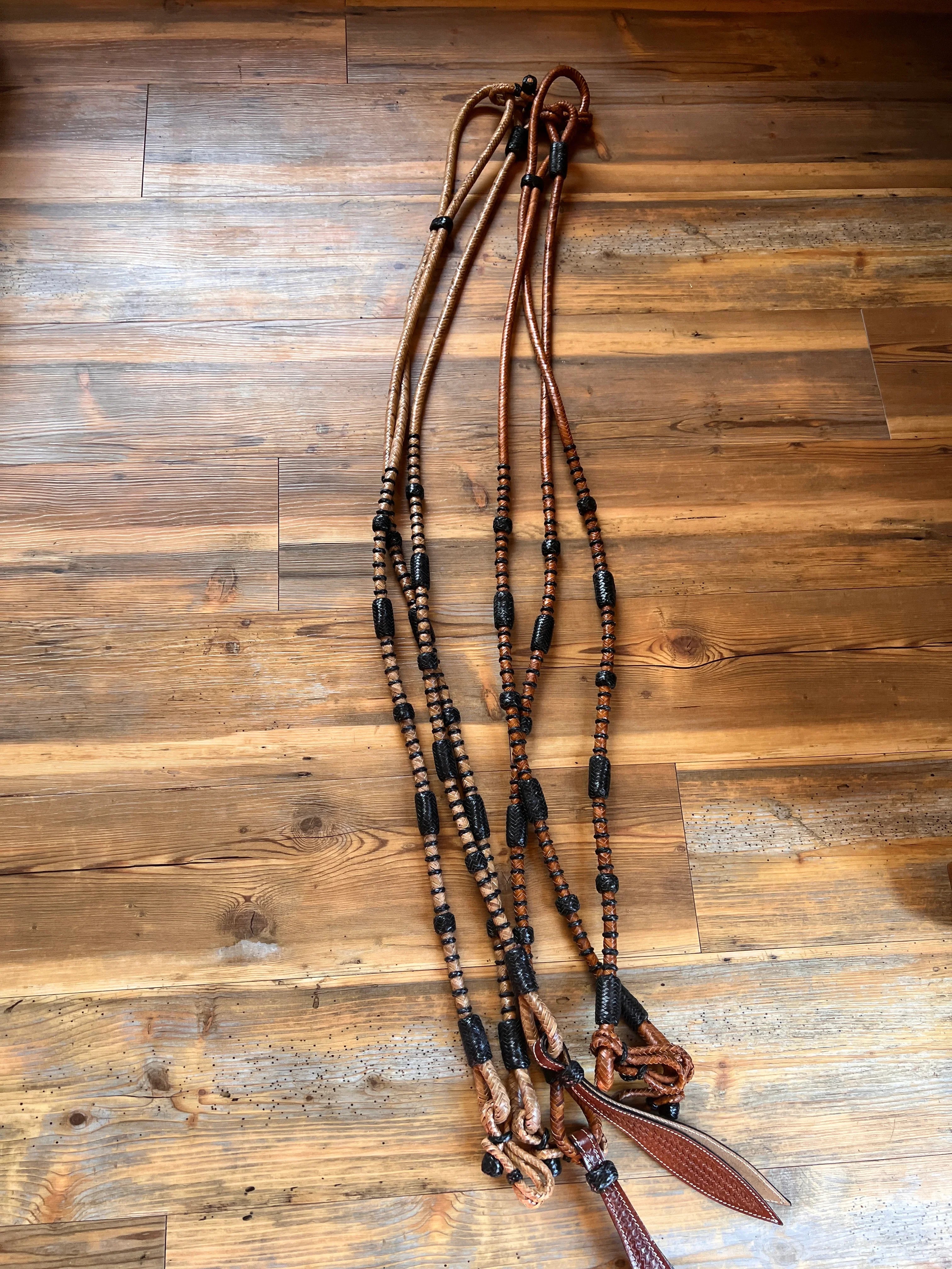 Romal reins with black rawhide in brown leather, beaded accents, braiding