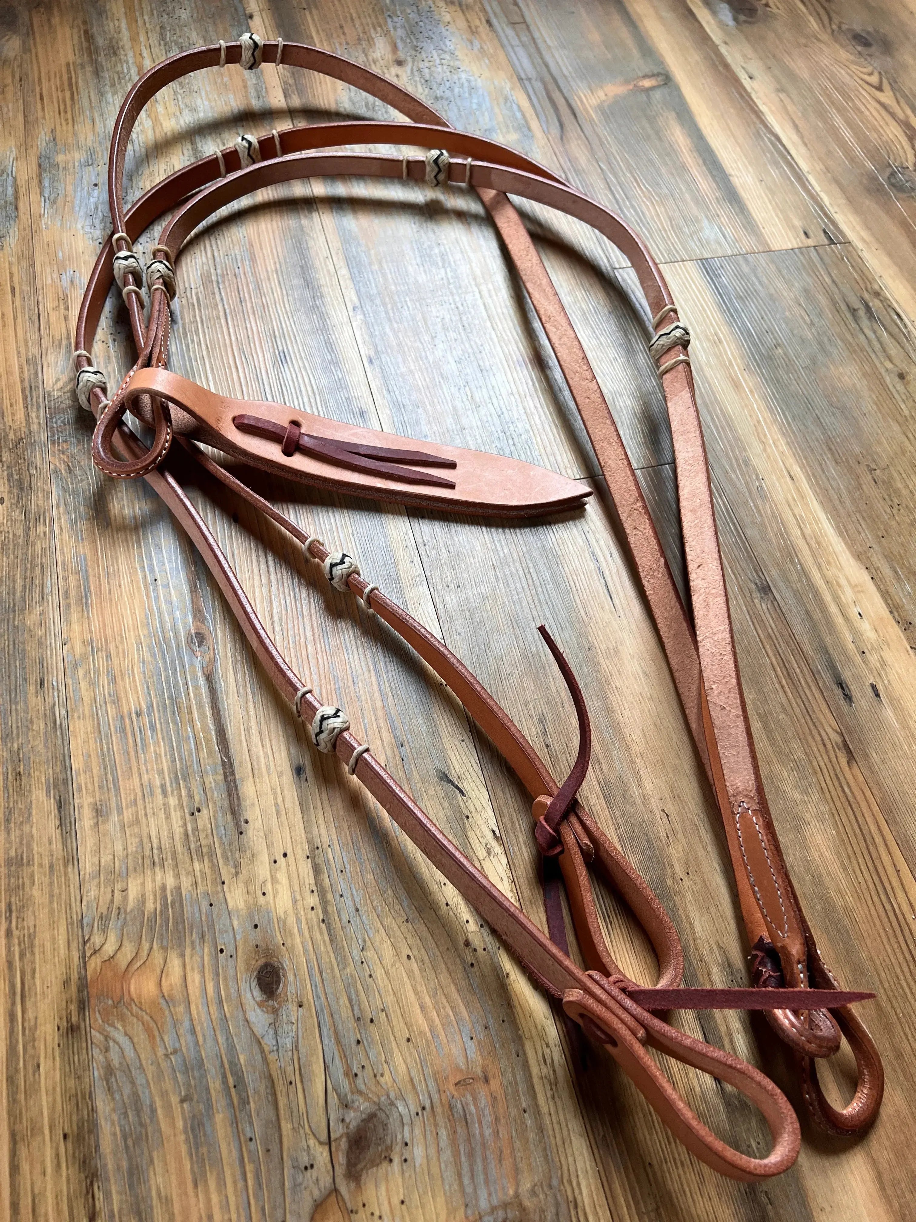 Tan leather horse halter with braided accents on 8 Flat Leather Romal Reins