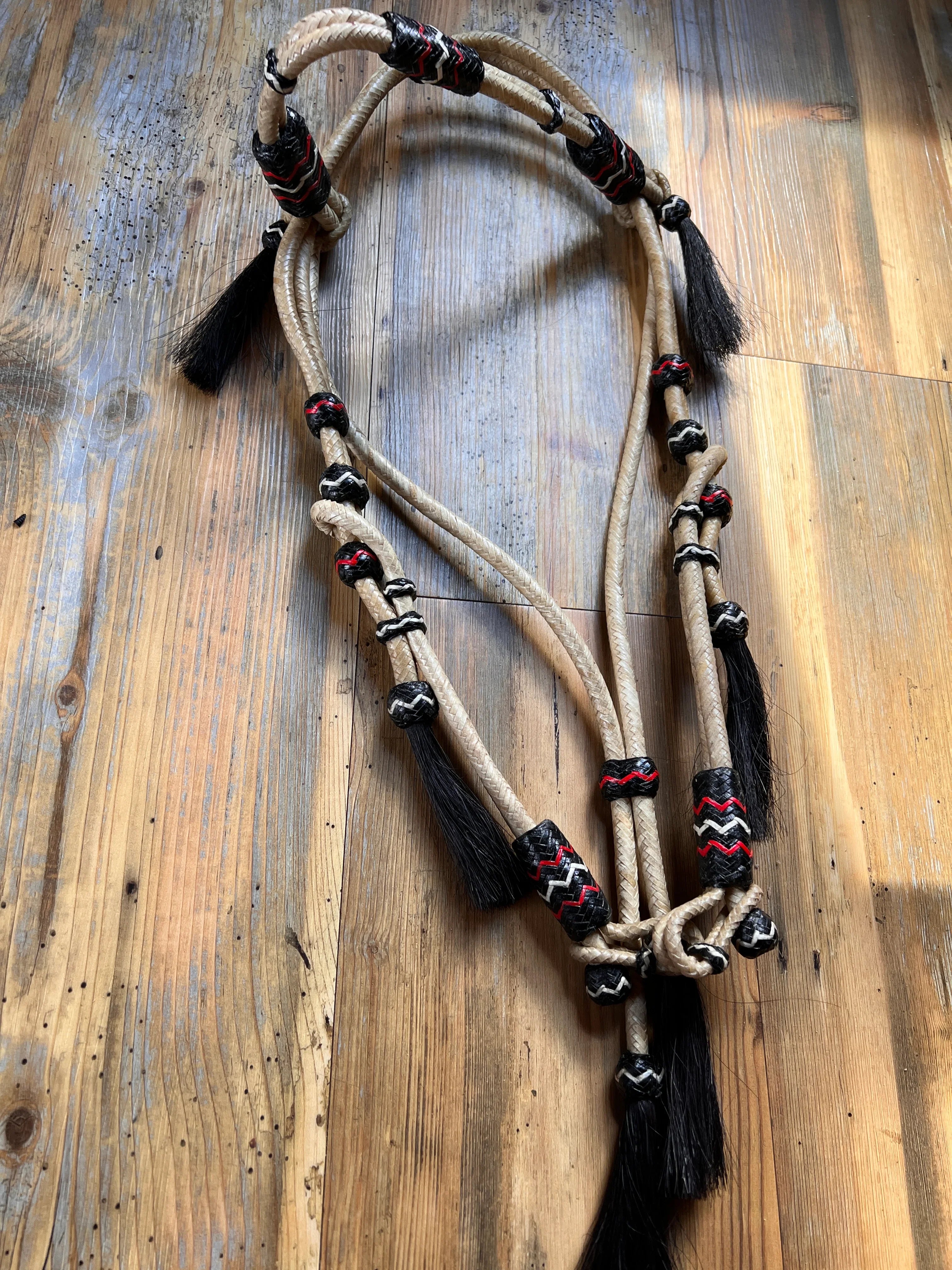 Beige braided rope halter with black tassels and red-black zigzag knots