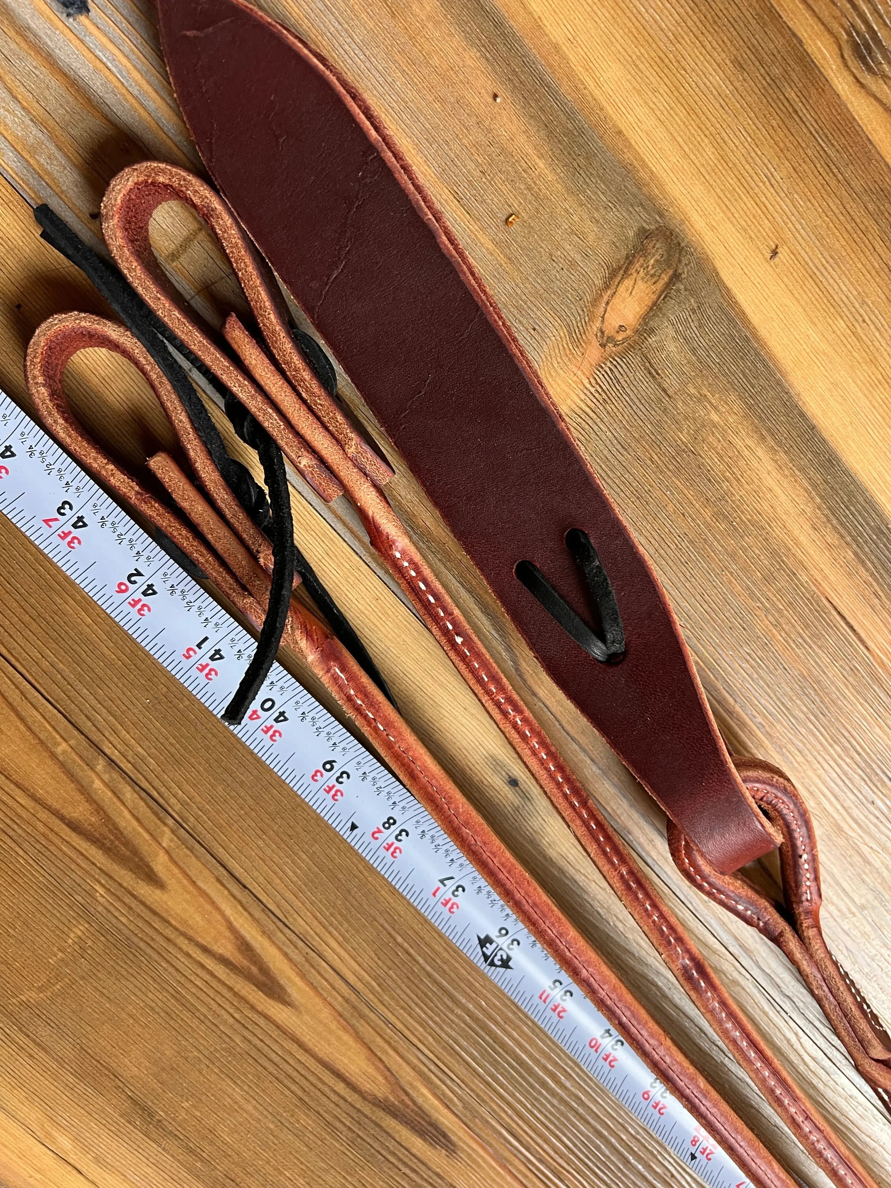 Brown leather romal reins with black stitching, popper and USA-made strap