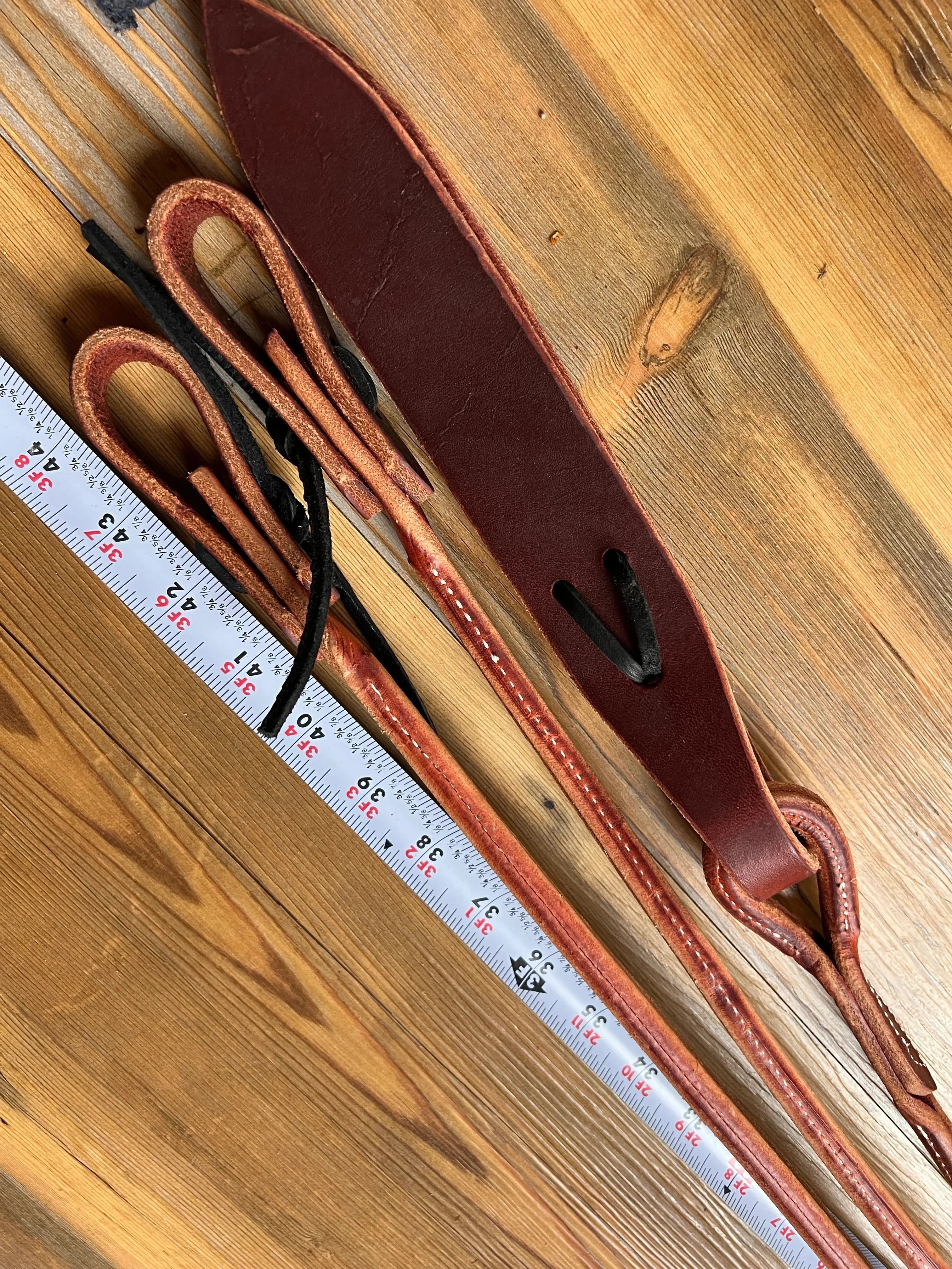 Brown leather romal reins with black stitching, popper and USA-made strap