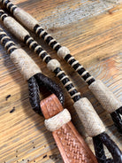 Black and beige 10-plait braided romal reins with tan tooled buckle, 55