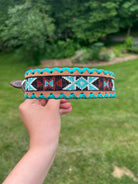 Hand holding turquoise brown beaded leather dog collar with geometric inlay