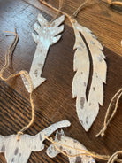 Weathered silver and tan cowhide feather arrow ornaments with twine