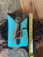 Back of acid wash teal turquoise cowhide saddle bag rear cinch with brown leather accents and ornate metal buckles