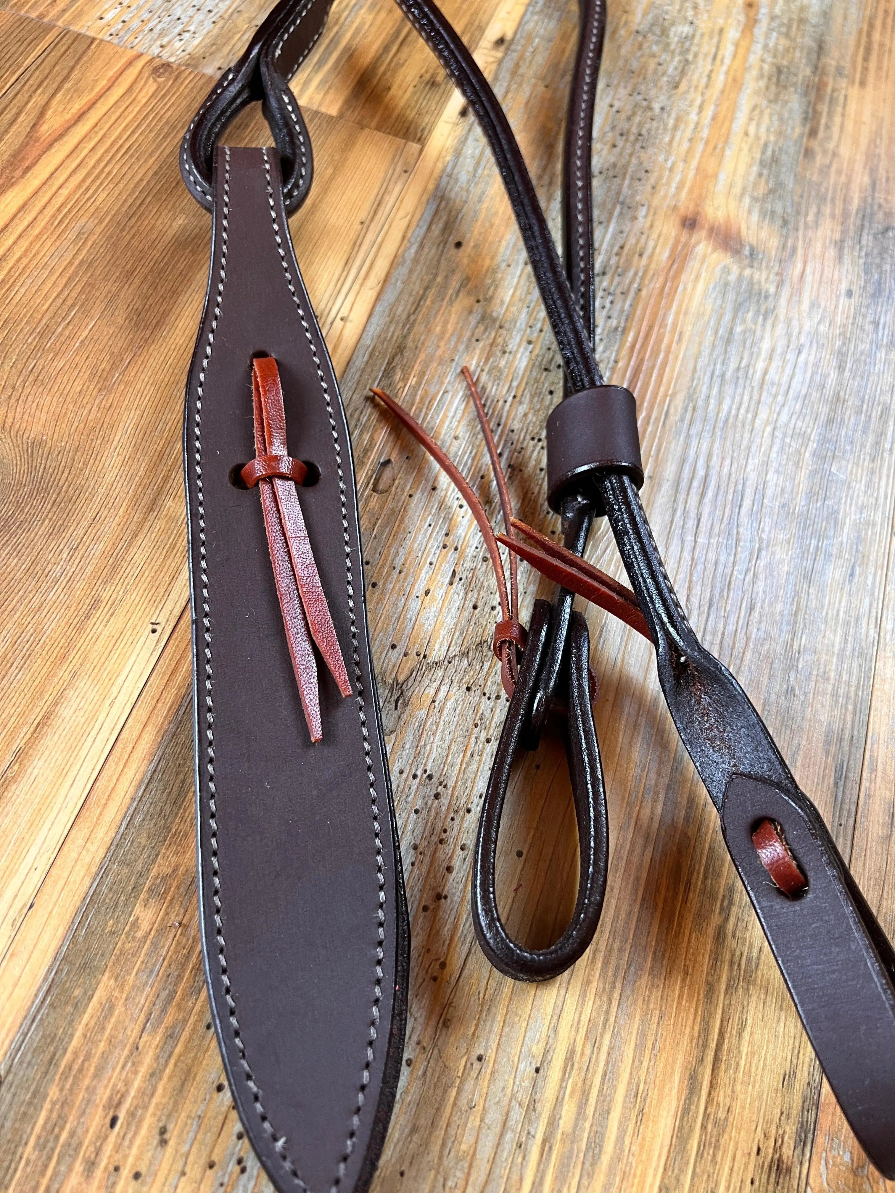 Dark brown leather romal reins strap with red stitching and tassels