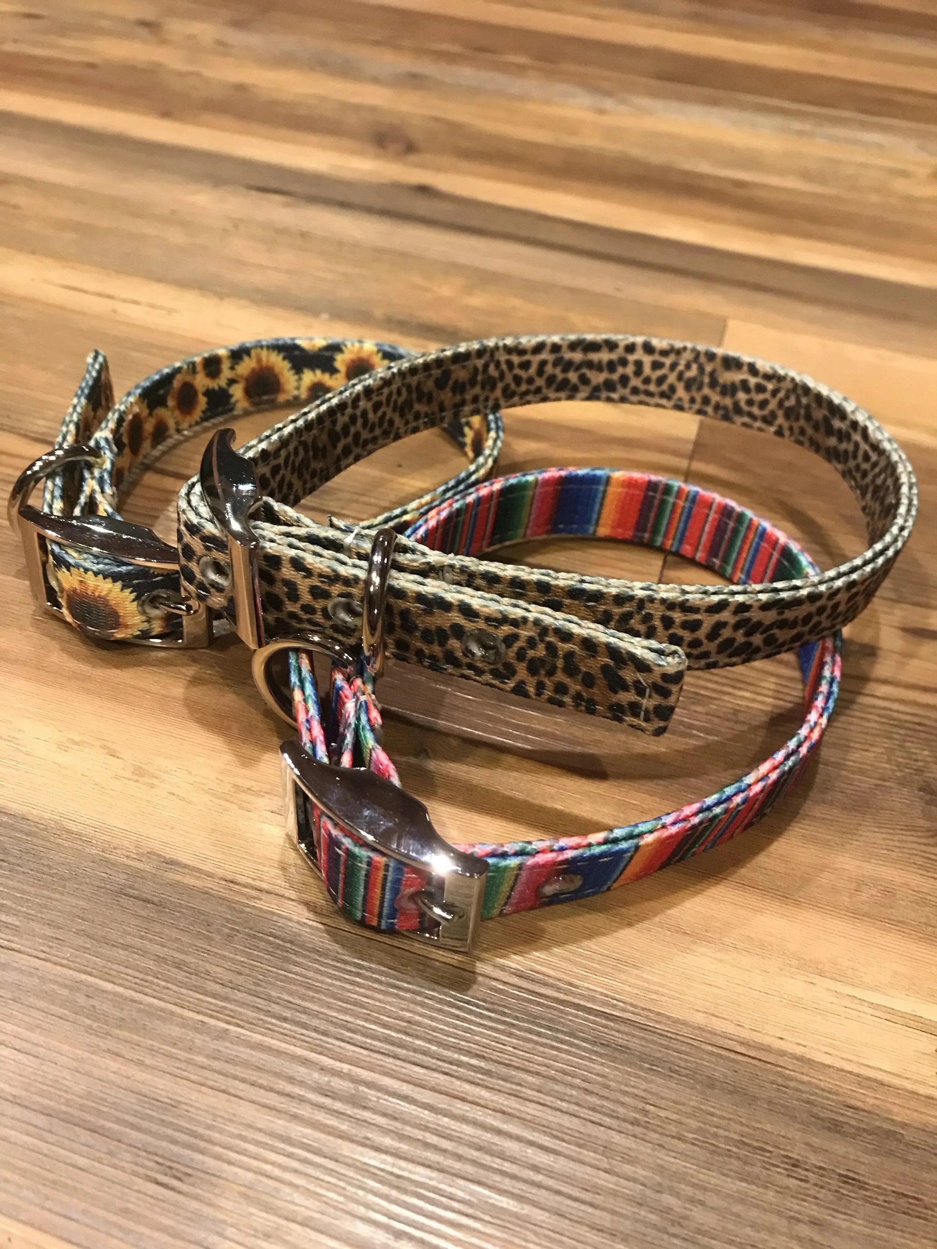 Three dog collars with metallic buckles in leopard, sunflower, striped patterns